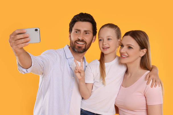 Happy family taking selfie on orange background - Photo, Image