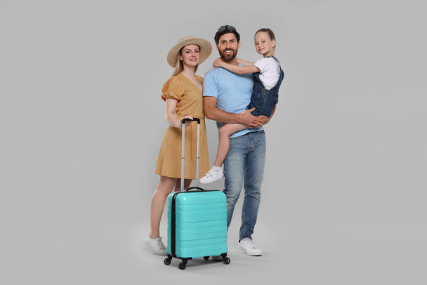 Happy family with turquoise suitcase on light grey background - Foto, afbeelding