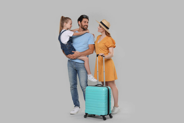 Happy family with turquoise suitcase on light grey background - Photo, Image