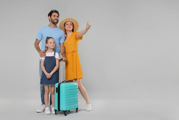 Happy family with turquoise suitcase on light grey background. Space for text - Fotografie, Obrázek