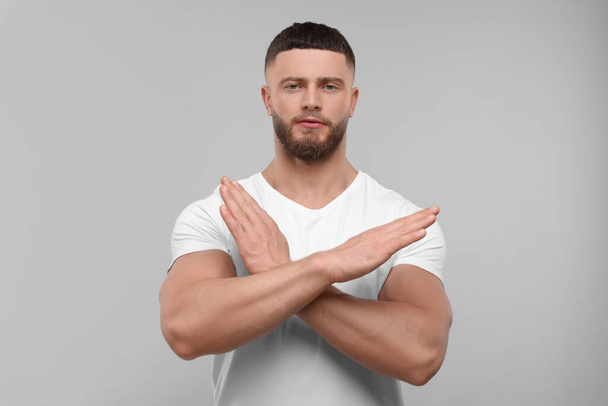 Stop gesture. Man with crossed hands on light grey background - Photo, image