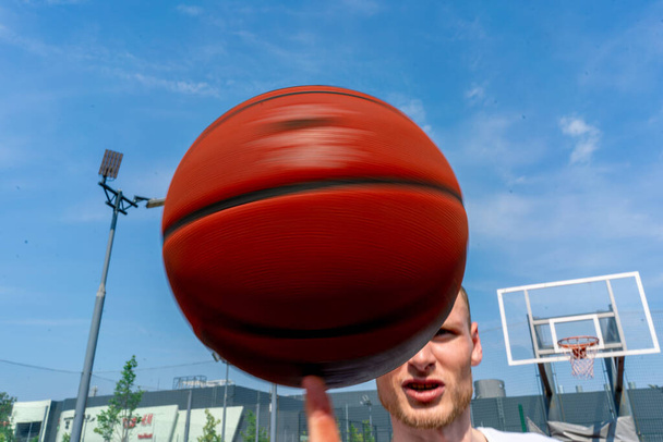 Close-up of guy basketball player spinning a basketball on his finger showing his basketball freestyle skills - Valokuva, kuva