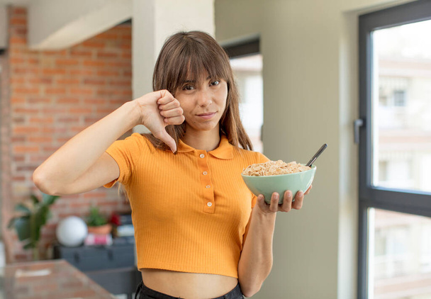 young pretty woman feeling cross,showing thumbs down. breakfast bowl concept - Foto, Imagem