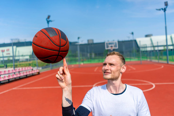 zbliżenie facet koszykarz przędzenie koszykówka na jego palec pokazując jego koszykówka freestyle umiejętności - Zdjęcie, obraz