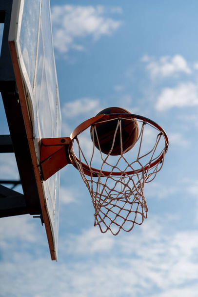 Ένα κοντινό πλάνο του μπάσκετ στεφάνι στο οποίο ένα μπάσκετ χτυπά την έννοια του θαυμασμού για το παιχνίδι του μπάσκετ και την αγάπη της άσκησης - Φωτογραφία, εικόνα