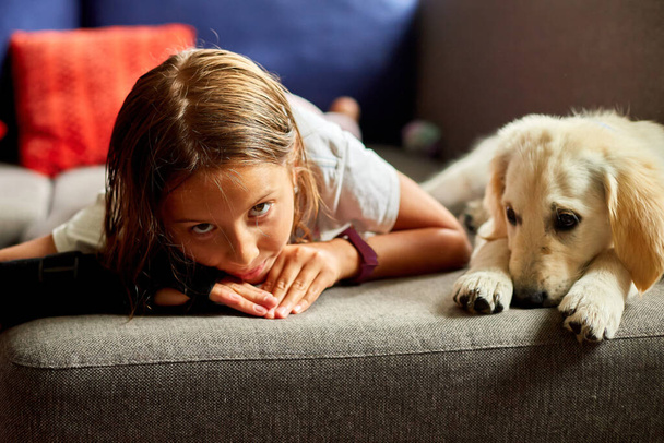 Glückliche Teenager-Mädchen auf dem Sofa liegend und umarmt ihren Welpen Golden Retriever Haustier, Liebe Haustiere, Freunde zu Hause - Foto, Bild