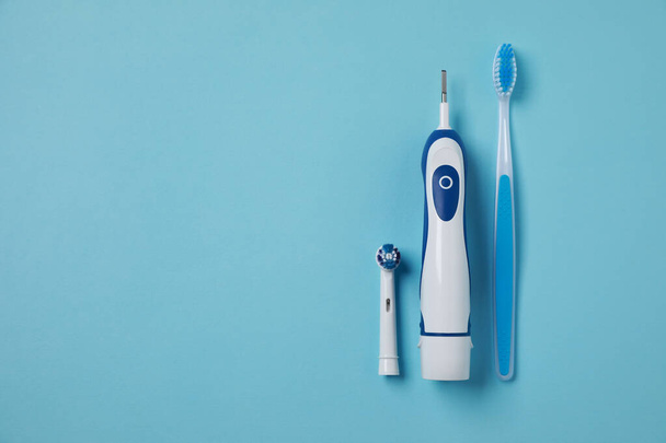 Electric and plastic toothbrushes on turquoise background, flat lay. Space for text - Photo, image