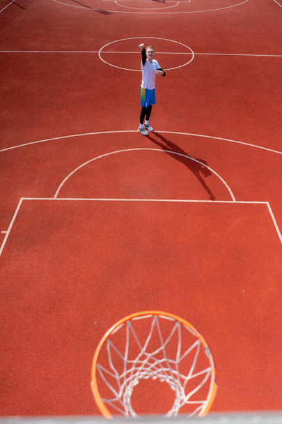 Primer plano del anillo de baloncesto en el que un jugador de baloncesto de hombre alto lanza la pelota El concepto de admirar el juego de baloncesto - Foto, imagen