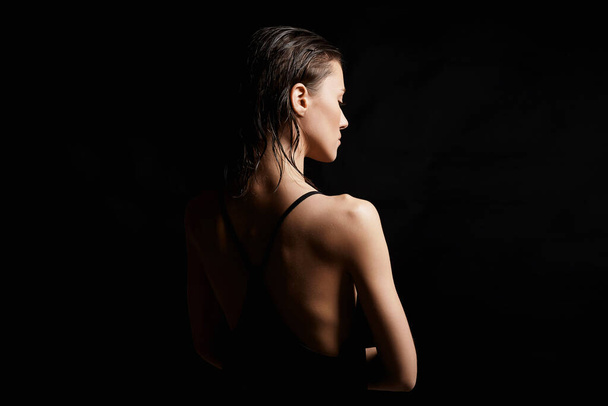 Hübsche junge Frau mit nassen Haaren. Schöne sexy Modell Mädchen in schwarzem Kleid. Weiblicher Rücken - Foto, Bild