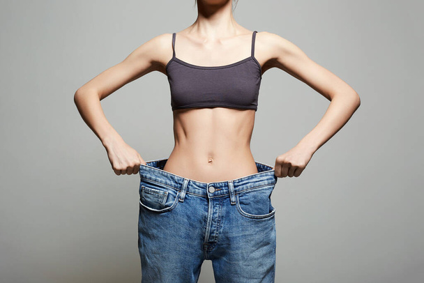 slimming Young woman in jeans. low waist. Beautiful Thin body Girl. Studio portrait - Photo, Image