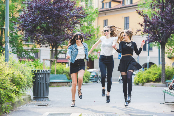 Trois jeunes belles femmes cacuasiennes milléniaux en plein air dans la ville courir et sauter en s'amusant en souriant bonheur, amitié, concept irréfléchi - Photo, image