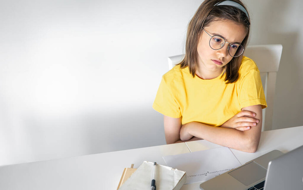 Уставшая школьница, страдающая от домашней работы, уставшая от учебы дома, готовящаяся к экзаменам, напряженная с трудной задачей, читающая книжка, пользующаяся ноутбуком. - Фото, изображение