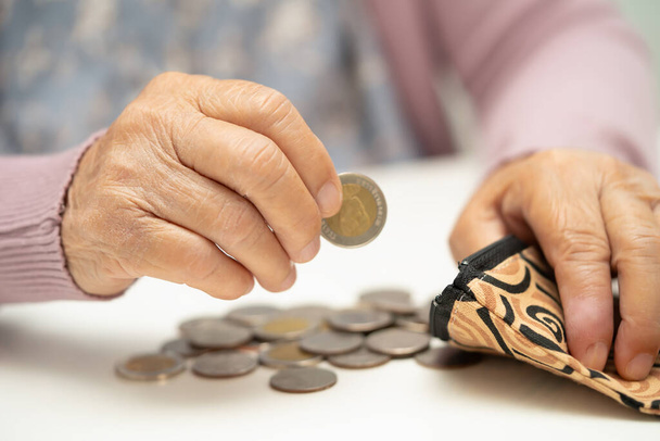 Asiatische Seniorin mit Münzgeld im Geldbeutel. Armut, Sparproblem im Ruhestand. - Foto, Bild