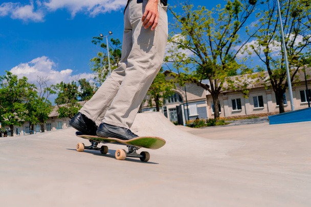 Joven skateboarder skateboarding alrededor de la ciudad skatepark junto a las figuras de acrobacias de cerca - Foto, imagen