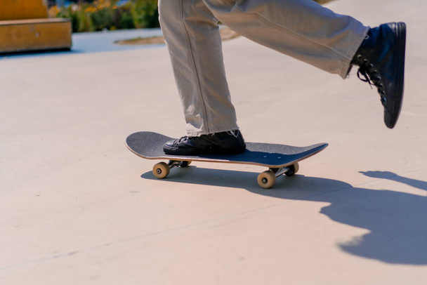 Joven skateboarder skateboarding alrededor de la ciudad skatepark junto a las figuras de acrobacias de cerca - Foto, imagen