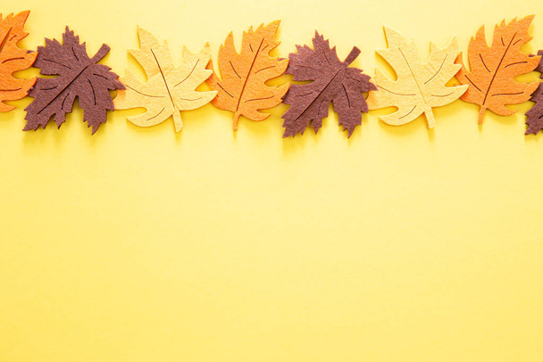 Fondo amarillo otoño con hojas de fieltro de colores, vista superior, espacio para copiar. - Foto, Imagen
