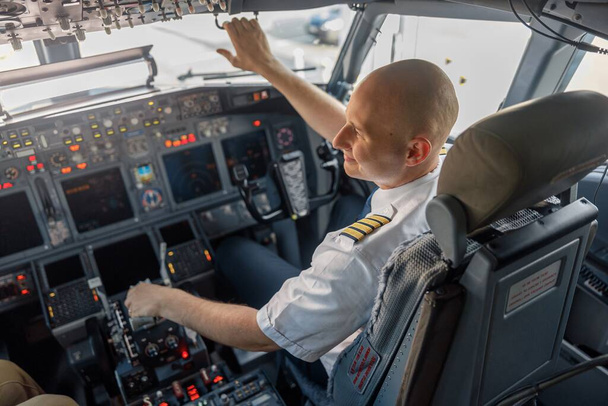 Vista de alto ângulo do piloto profissional sentado em uma cabine de avião, pronto para decolagem. Aeronaves, tripulação, conceito de ocupação - Foto, Imagem