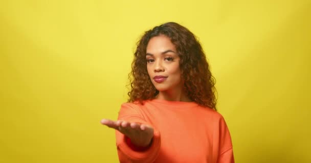 Flört eden genç bir kadın, sarı stüdyo geçmişiyle seni çağırıyor. Yüksek kalite 4k görüntü - Video, Çekim