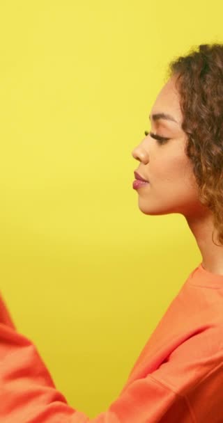 Perfil de mujer joven pensando, contemplando la mano bajo la barbilla, estudio amarillo. Imágenes de alta calidad 4k - Imágenes, Vídeo
