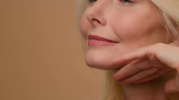 Közelkép Kaukázusi érett idős ráncos nő középkorú gyönyörű modell stúdió touch nyak puha hidratált bőrápoló spa eljárás alkalmazni öregedés elleni kozmetikai emelés arc plasztikai sebészet - Felvétel, videó