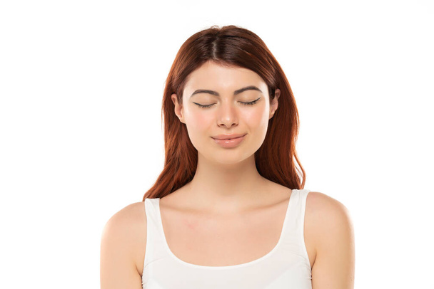 Portrait of smiling beautiful woman with long straight ginger hair and closed eyes on a white studio background - Photo, Image