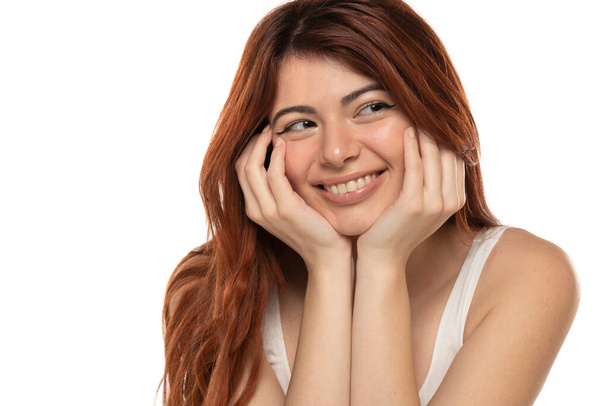 Портрет улыбающейся красивой женщины с длинными прямыми рыжими волосами на белом фоне студии - Фото, изображение