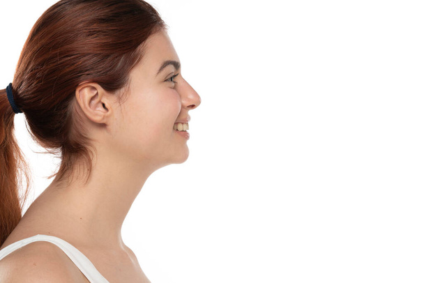 profilja egy fiatal mosolygós vörös hajú nő smink nélkül hosszú haj egy fehér stúdió háttér - Fotó, kép
