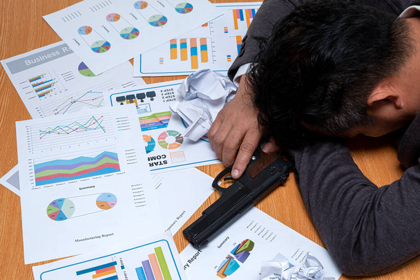 Криминальная напряженность в деловом мире: азиатский бизнесмен с пистолетом, спящим на столе - Фото, изображение