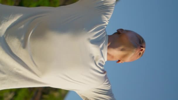 Güneş ışığında yoga yapan güçlü bir adam. Dağ manzarasında nefes alıp veren zinde bir adam. Güzel manzaraya dikey odaklı videoda odaklanmış kel yogi treni. Fitness yaşam tarzı konsepti - Video, Çekim