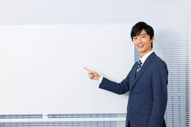 Young Japanese man pointing at the whiteboard - 写真・画像