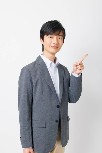 Young Japanese man in office attire showing pointing gesture - Photo, Image