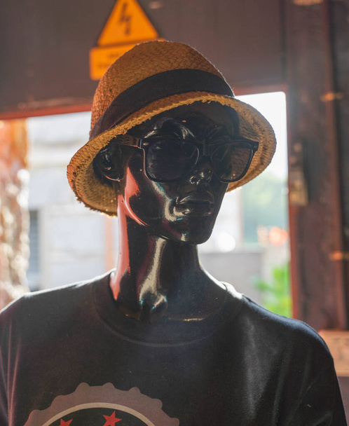 Чорний манекен з капелюхом і сонцезахисними окулярами розмістив підсвічування перед дверима - Фото, зображення