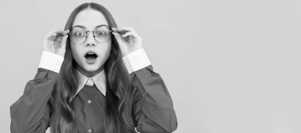 Shocked school aged girl child in spectacles with amazed look yellow background, amazement. Child face, horizontal poster, teenager girl isolated portrait, banner with copy space - 写真・画像