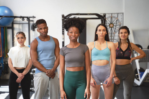 Group of sportive people looking at camera while posing together in the gym. Sport and healthy lifestyle concept. - Photo, Image