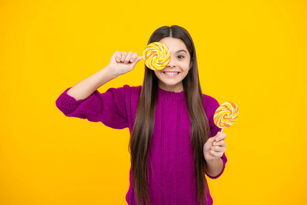 Teen girl hold lollipop caramel on yellow background, candy shop. Teenager with sweets suckers - Photo, Image