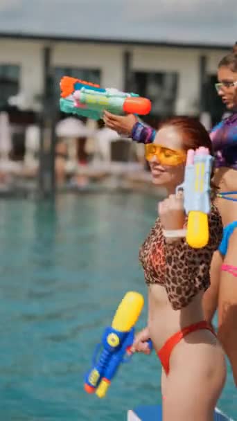 A visão de jovens meninas animadas dançando com armas de água perto da piscina é um espetáculo alegre. Imagens 4k de alta qualidade - Filmagem, Vídeo