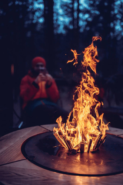 Los hombres sentados cerca de camping fuego hombre cerca del fuego de camping - Foto, Imagen