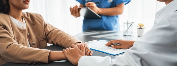 Doctor show medical diagnosis report and providing compassionate healthcare consultation while holding young patient hand for being supportive and professional in doctor clinic office. Neoteric - Foto, Bild