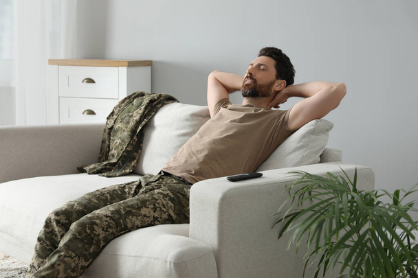 Soldier napping on soft sofa in living room. Military service - Φωτογραφία, εικόνα