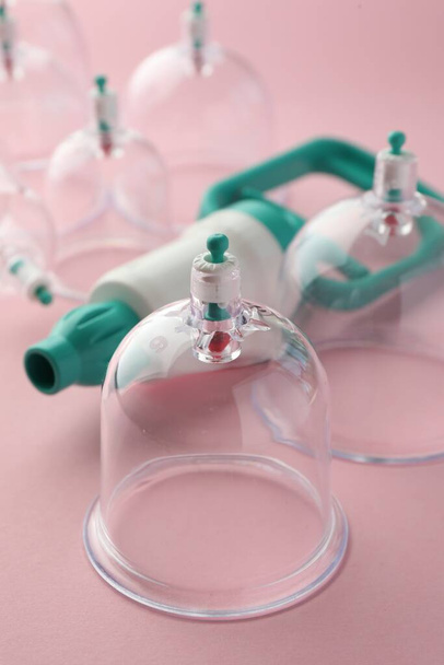 Plastic cups and hand pump on pink background, closeup. Cupping therapy - Photo, image