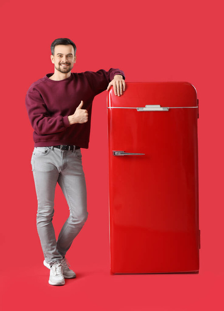Handsome man with big blank poster showing thumb-up on red background - Φωτογραφία, εικόνα