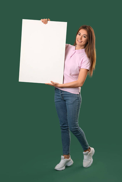 Beautiful woman with big blank poster on green background - Foto, afbeelding