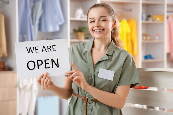 Female sales consultant with opening sign in boutique - Photo, Image