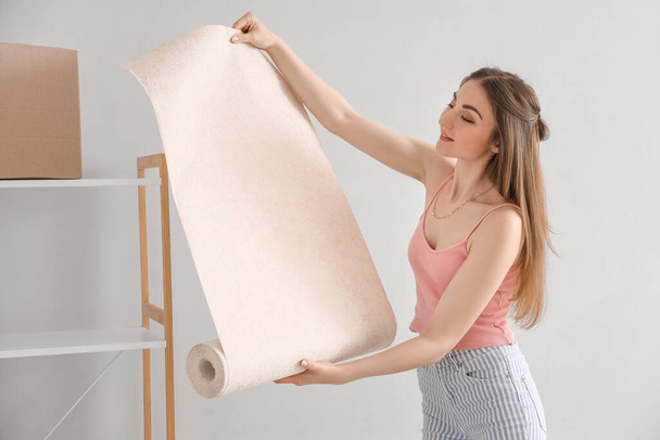 Jovem mulher com papel de parede rolo em casa - Foto, Imagem