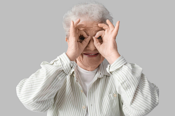 Divertente donna anziana su sfondo grigio - Foto, immagini