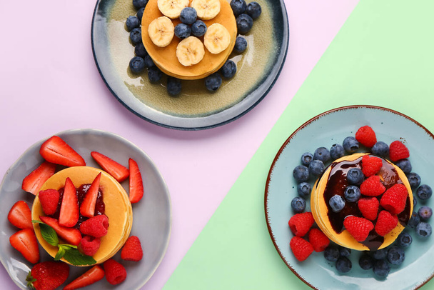 Plates with sweet pancakes and berries on color background - Photo, Image