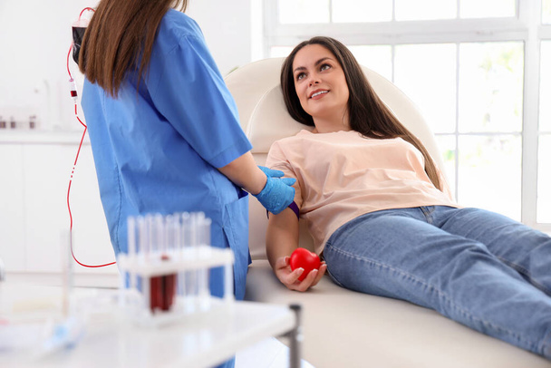 Doctora preparando donante joven para transfusión de sangre en clínica - Foto, Imagen