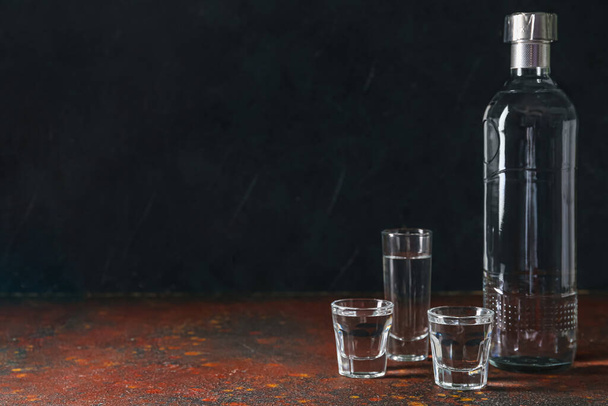 Bottle and glasses of vodka on table - Фото, изображение