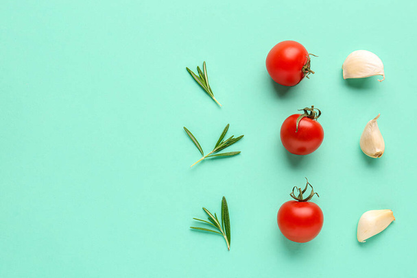 Composition with ripe cherry tomatoes, rosemary and garlic on turquoise background - Foto, Imagen