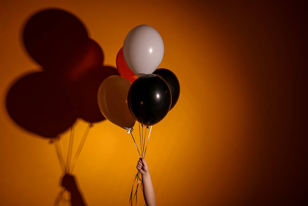 Female hand with Halloween balloons on orange background - Foto, immagini